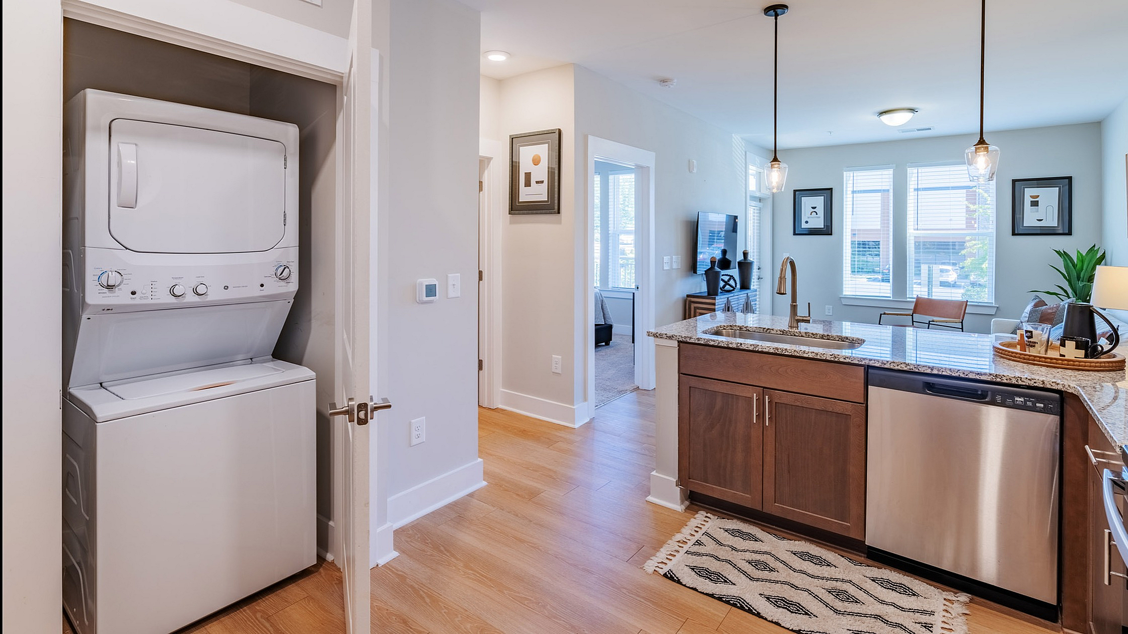 Modern, bright apartment featuring an open-concept kitchen with elegant wood cabinets, granite countertops, and a convenient in-unit washer and dryer.