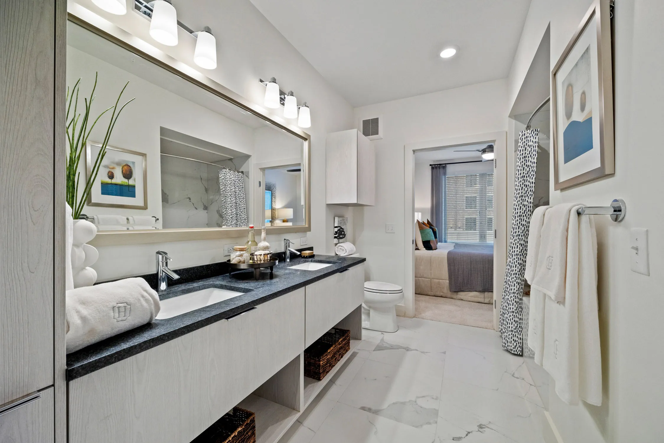 Luxurious bathroom with sleek double vanity, elegant lighting, and a glimpse into a cozy bedroom, creating a seamless blend of comfort and style.