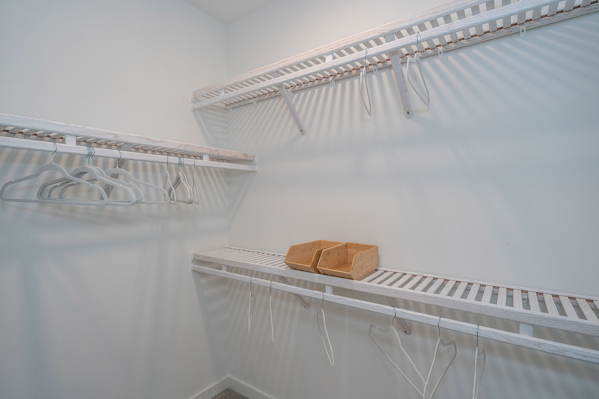 Spacious walk-in closet with elegant shelving and stylish wooden storage boxes.