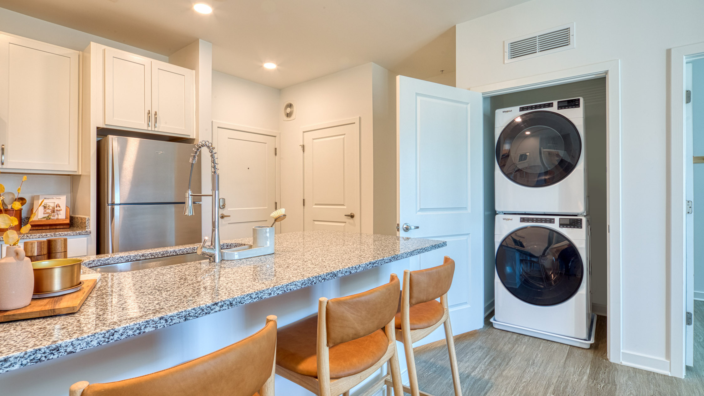 Modern kitchen with granite countertops, stainless steel appliances, and in-unit washer and dryer in a stylish apartment.