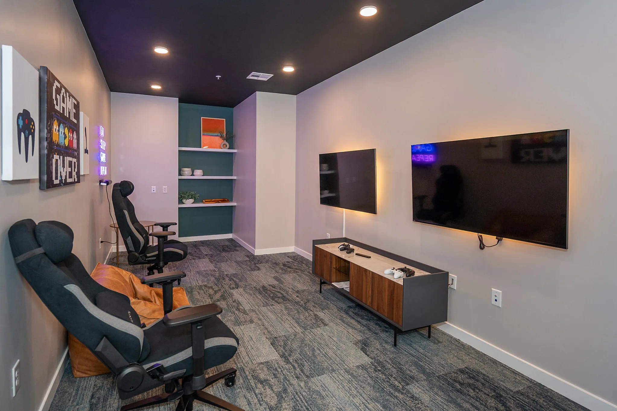 Modern gaming room with sleek setup featuring dual screens, ergonomic chairs, and vibrant wall art for an immersive experience.