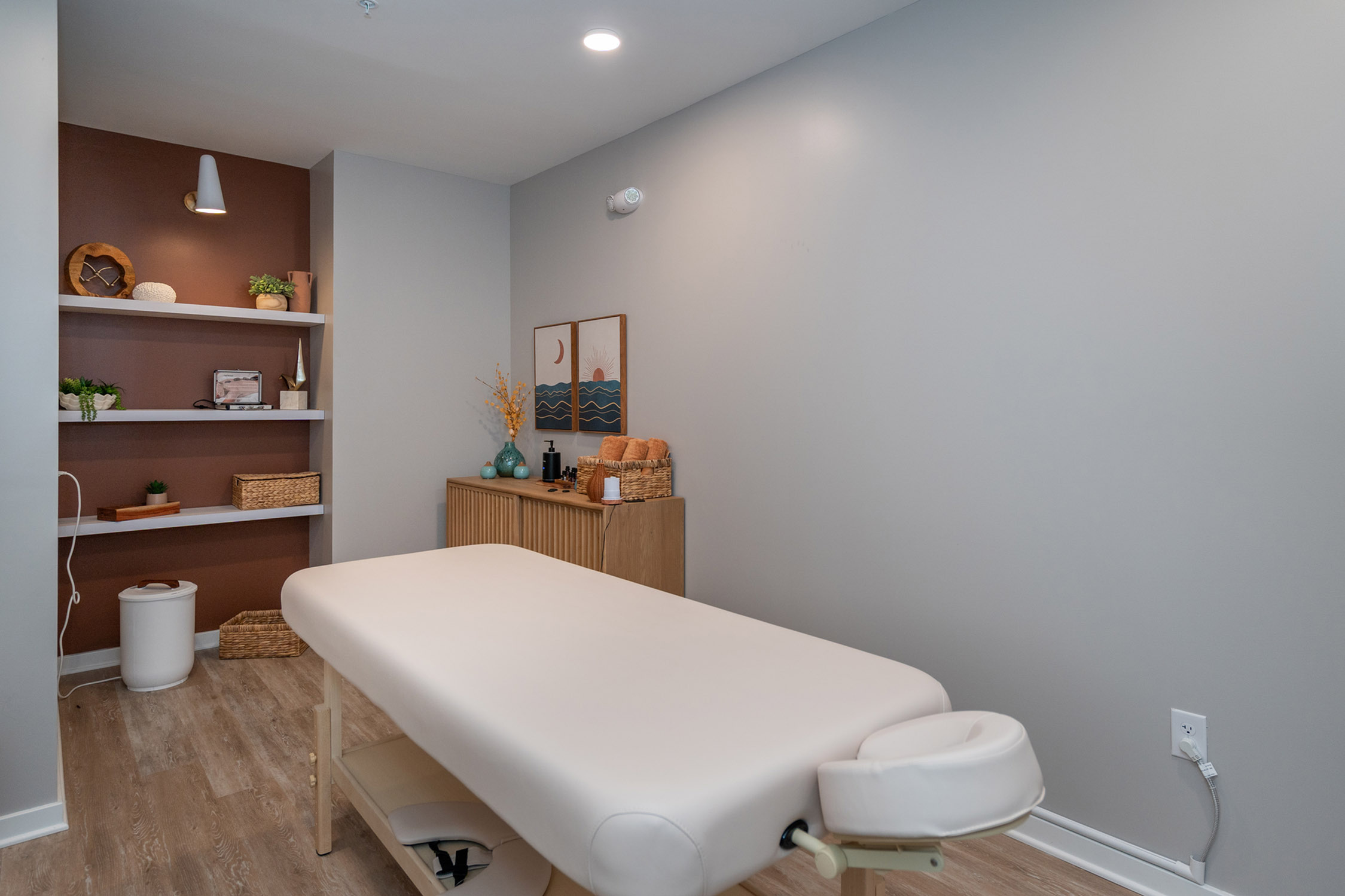 Inviting massage room featuring a plush massage table, elegant wooden decor, and calming earth-tones for a serene atmosphere.