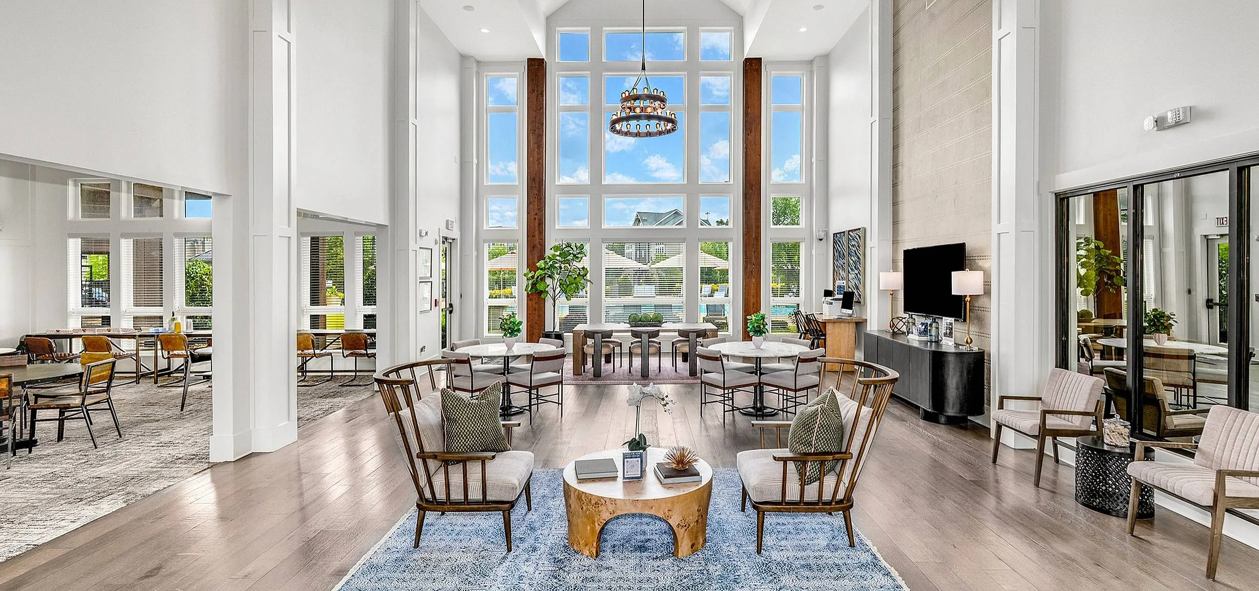 Luxurious open-concept living space with vaulted ceilings, elegant wood beams, and a vibrant view through large windows, perfect for entertaining.