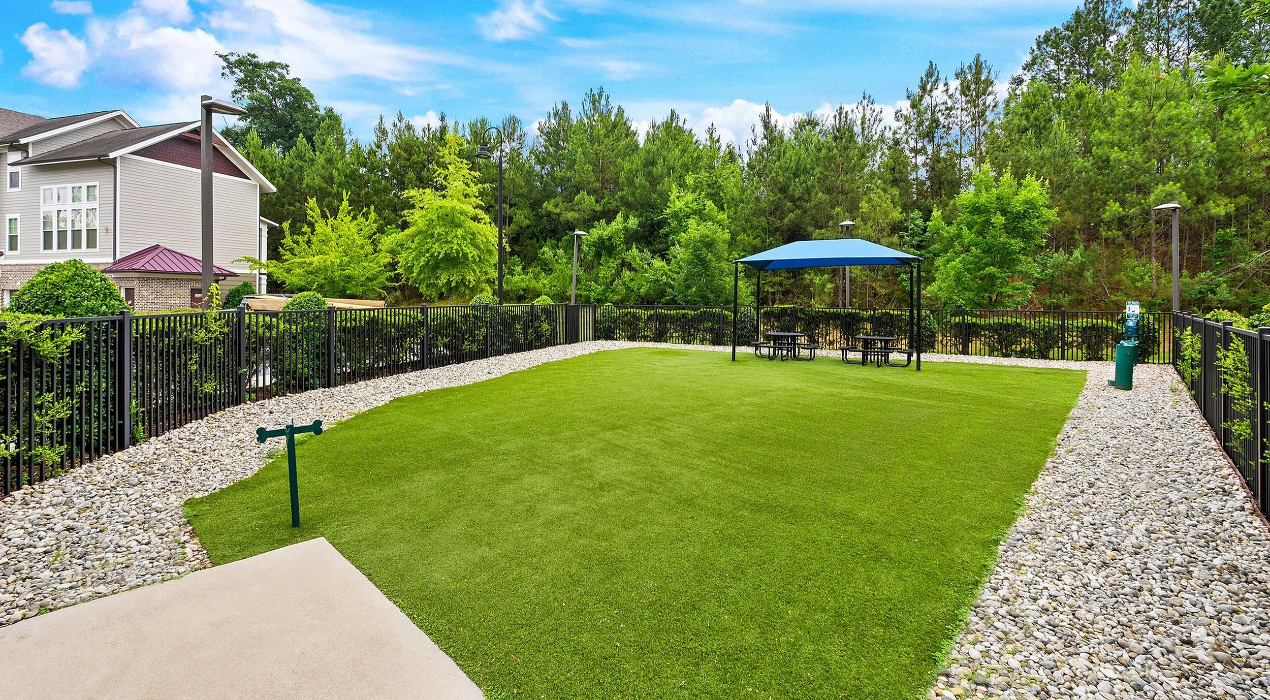 Inviting outdoor space with lush green lawn, stylish gazebo, and tranquil wooded backdrop.