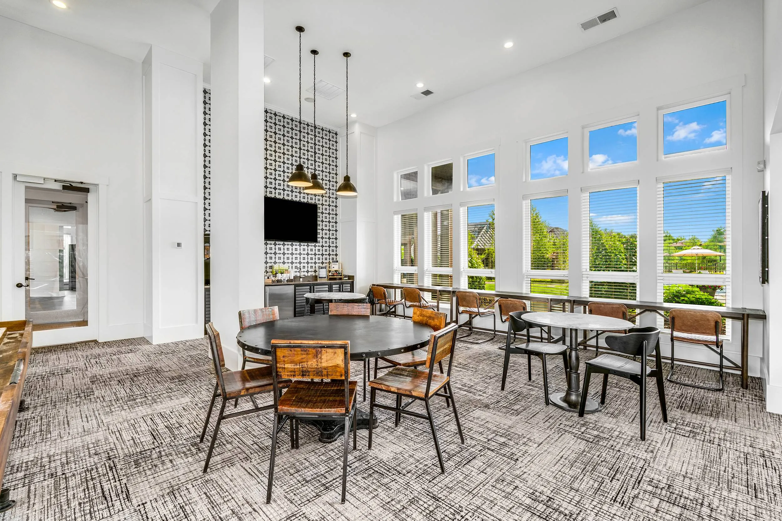 Bright, modern communal lounge area with large windows, stylish furniture, and accent lighting, offering a vibrant and inviting atmosphere.