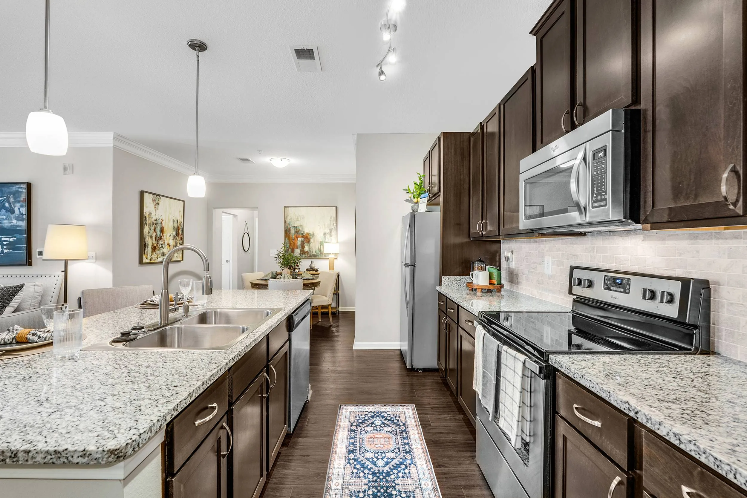 Sleek modern kitchen with granite countertops, stainless steel appliances, stylish pendant lighting, and a cozy dining area, ideal for entertaining.