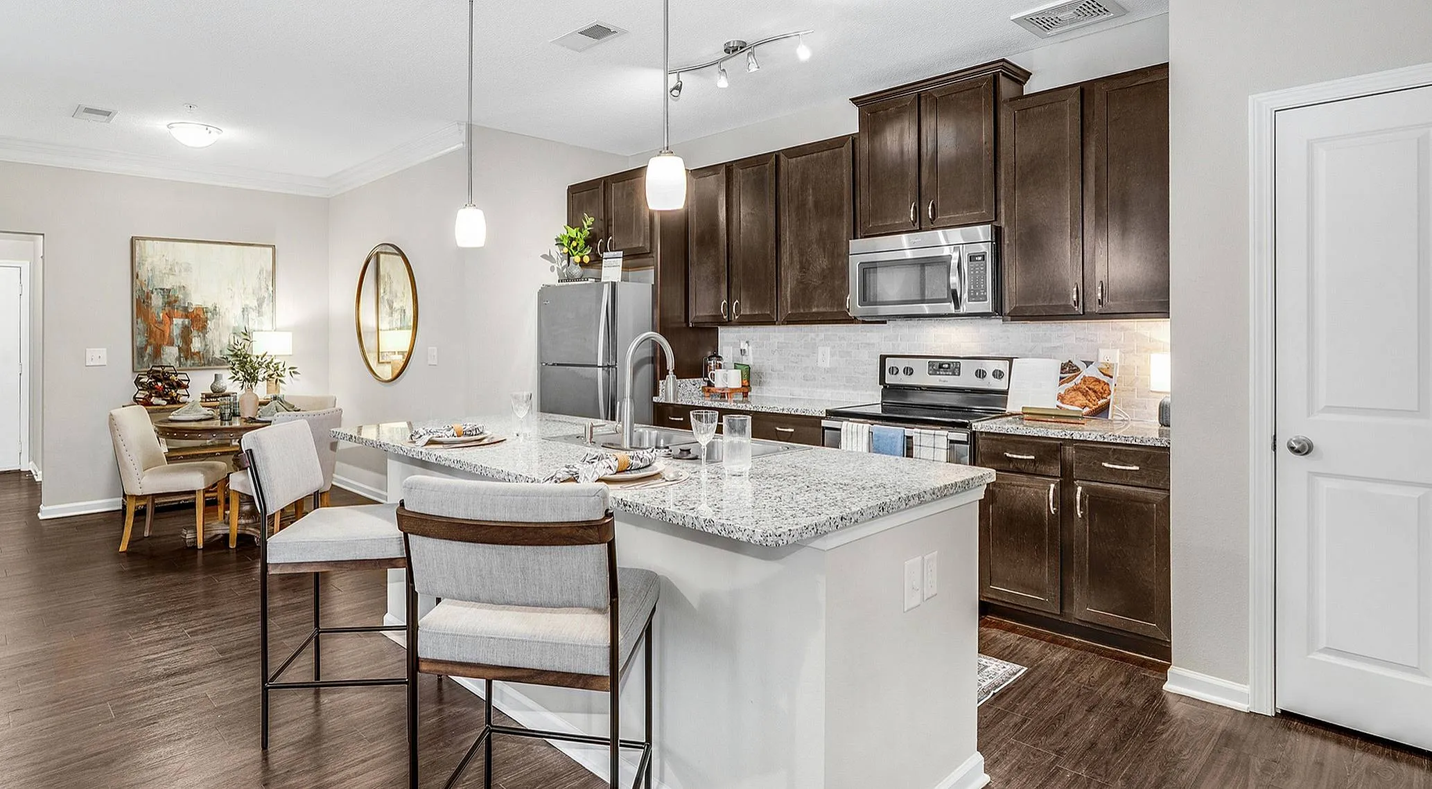 Chic open-concept kitchen and dining area with granite countertops and dark wood cabinets, perfect for entertaining.