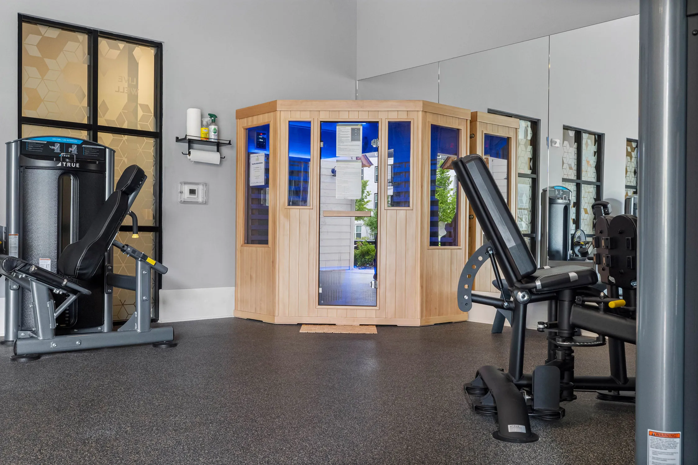 Modern fitness center with high-end exercise equipment and a stylish wooden sauna, offering a luxurious workout experience.