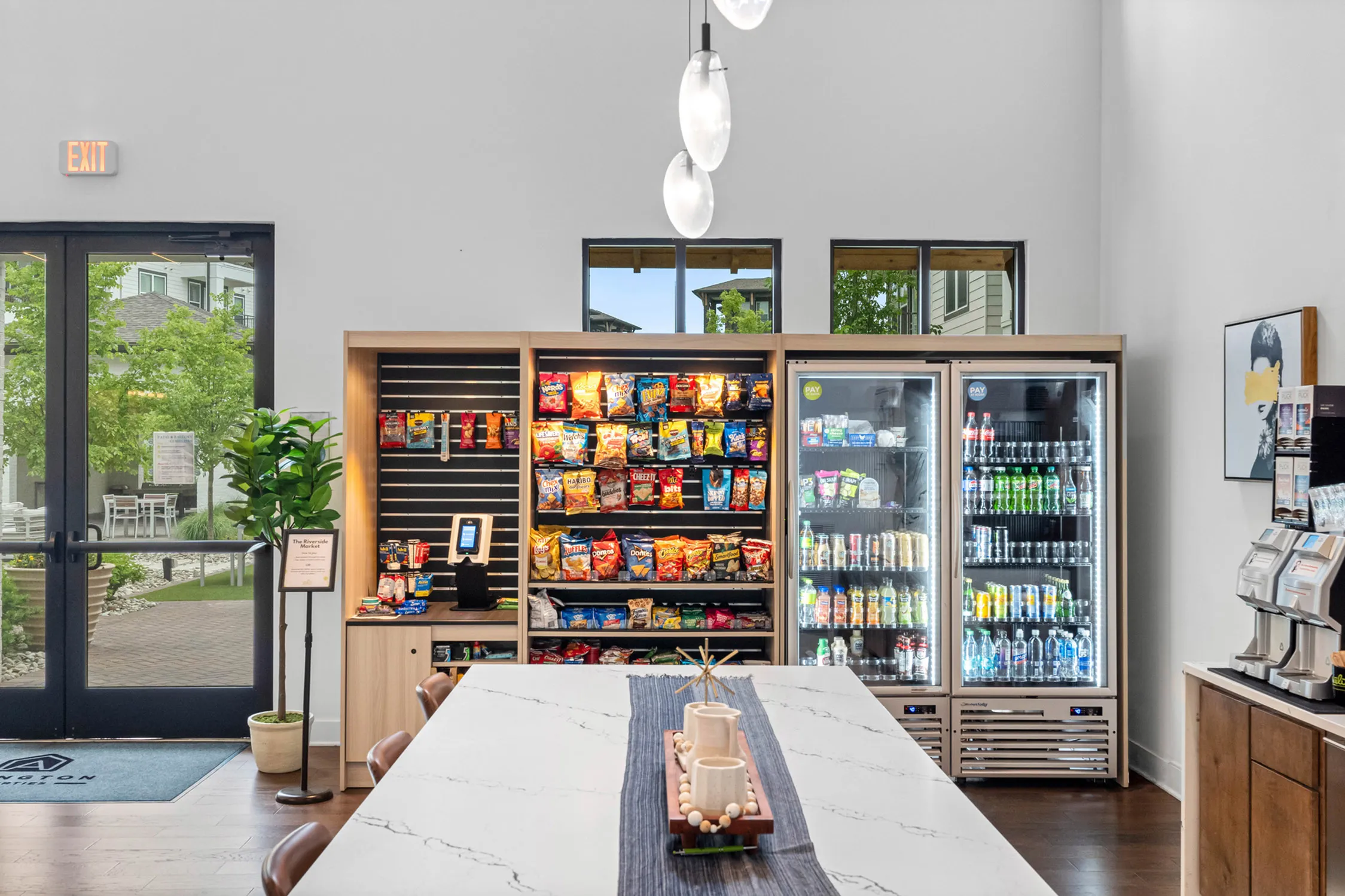 Modern retail snack area featuring well-stocked shelves of colorful snacks and beverages, with a sleek marble counter and cozy seating.