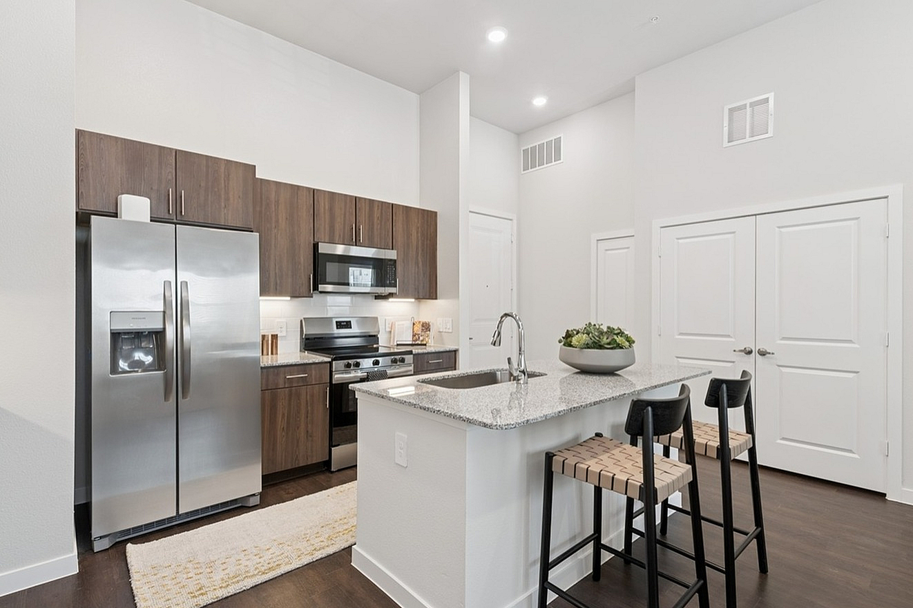 Modern kitchen with sleek granite countertops, stainless steel appliances, and elegant wooden cabinetry, creating a perfect blend of style and functionality.