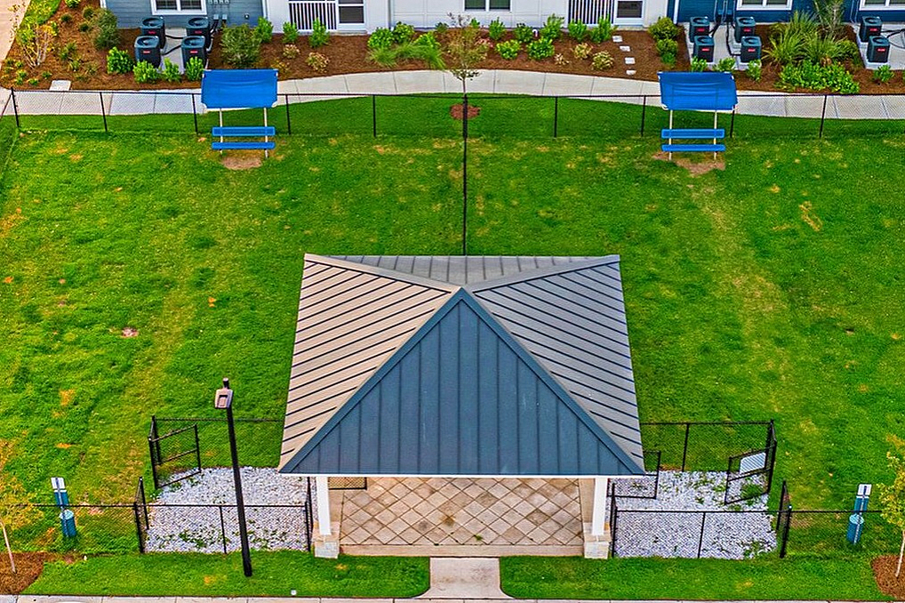 Contemporary apartment building with charming landscaping, ample parking, and a central outdoor pavilion, perfect for relaxation.