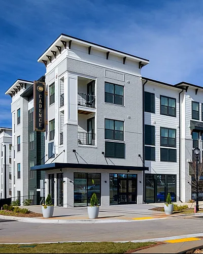 Modern four-story apartment complex with stylish architecture and ample parking space.