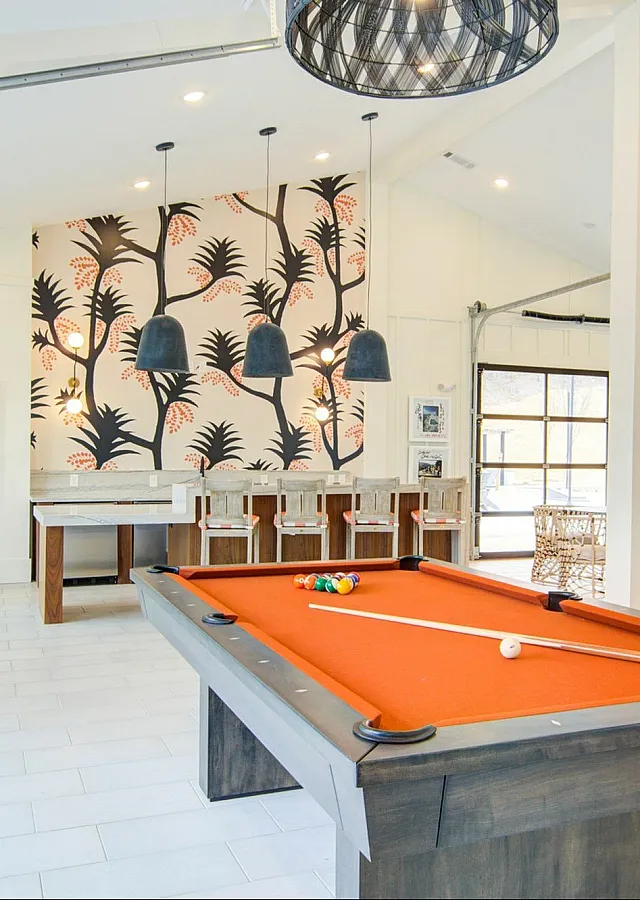 Stylish game room with orange pool table and vibrant wallpaper.