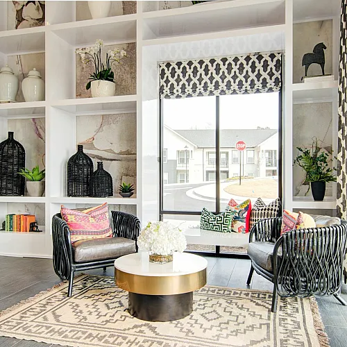 Contemporary styled living room with elegant shelving, cozy chairs, and large window displaying natural light.
