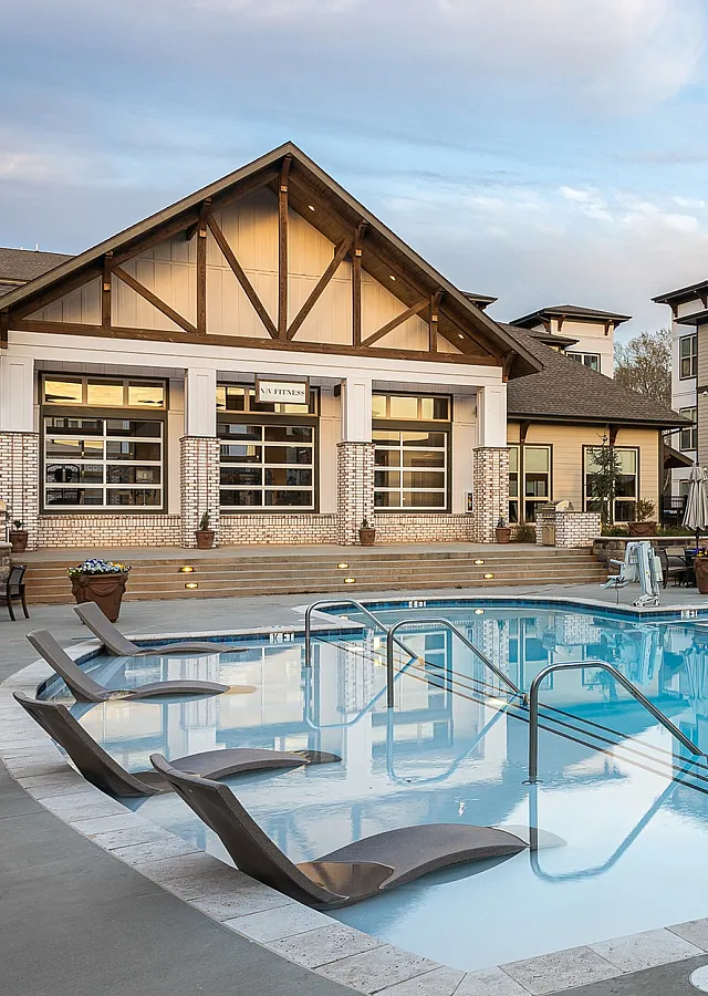Elegant apartment complex with a sparkling pool and stylish loungers.
