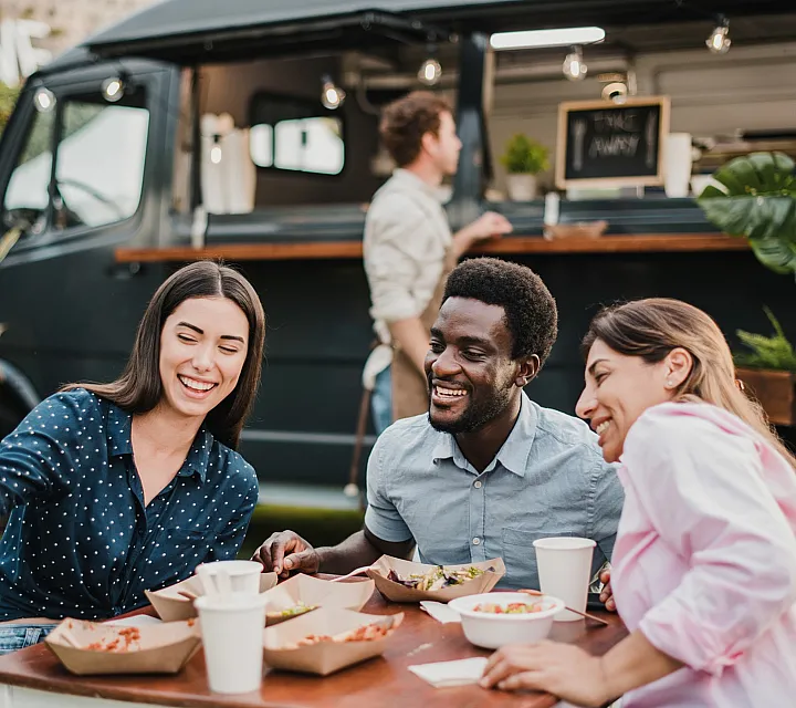 Group of friends enjoying a meal at a cozy outdoor food truck setting.