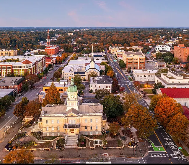 Aerial view of a vibrant city with historic architecture, tree-lined streets, and a prominent clock tower.