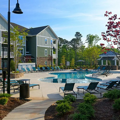 Inviting pool area surrounded by modern apartments and lush greenery, perfect for relaxation and enjoyment.