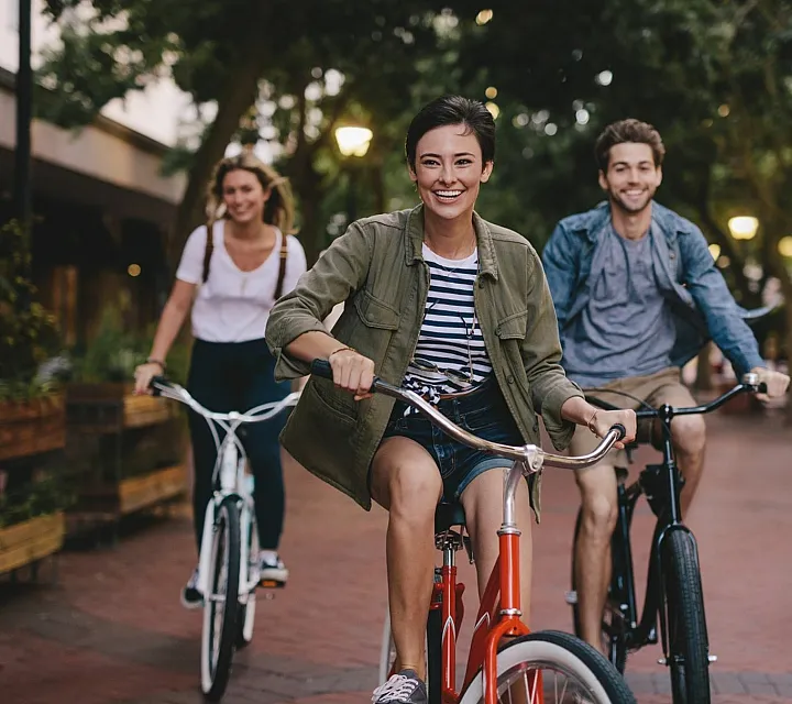 Three friends enjoy a leisurely bike ride through a tree-lined urban street.