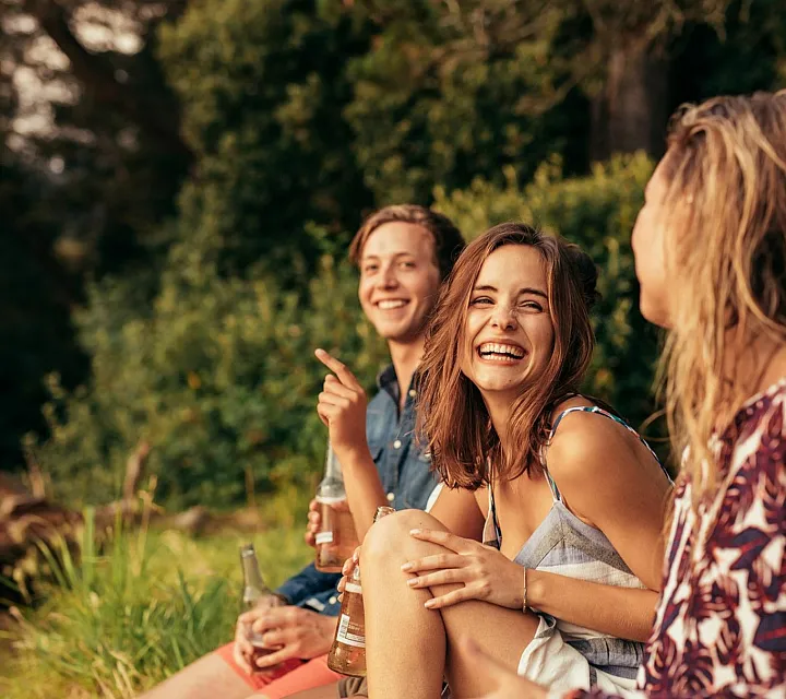 Group of friends laughing and enjoying a sunny day outdoors.