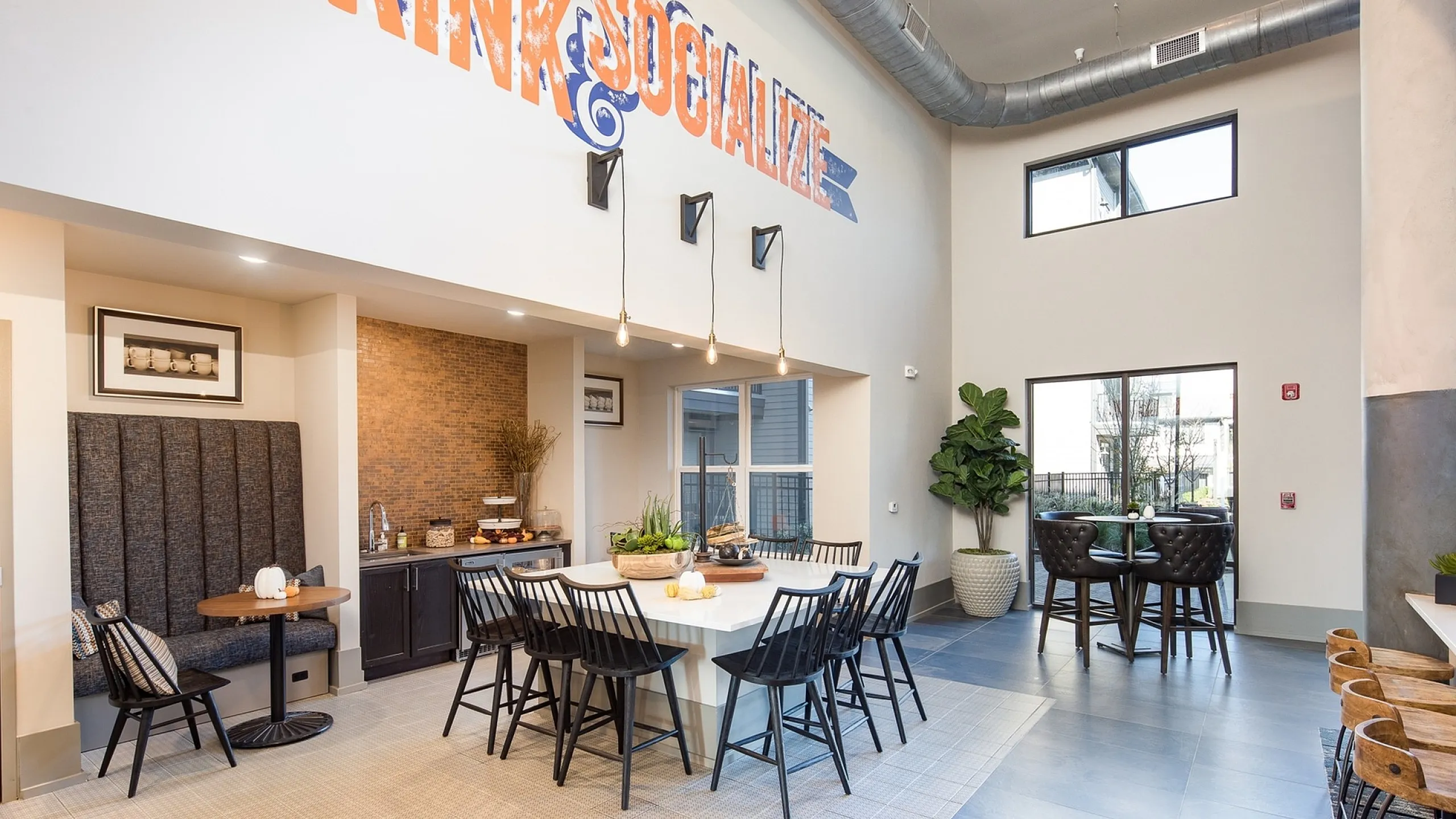 Inviting communal dining area with modern decor and 'Drink & Socialize' mural.
