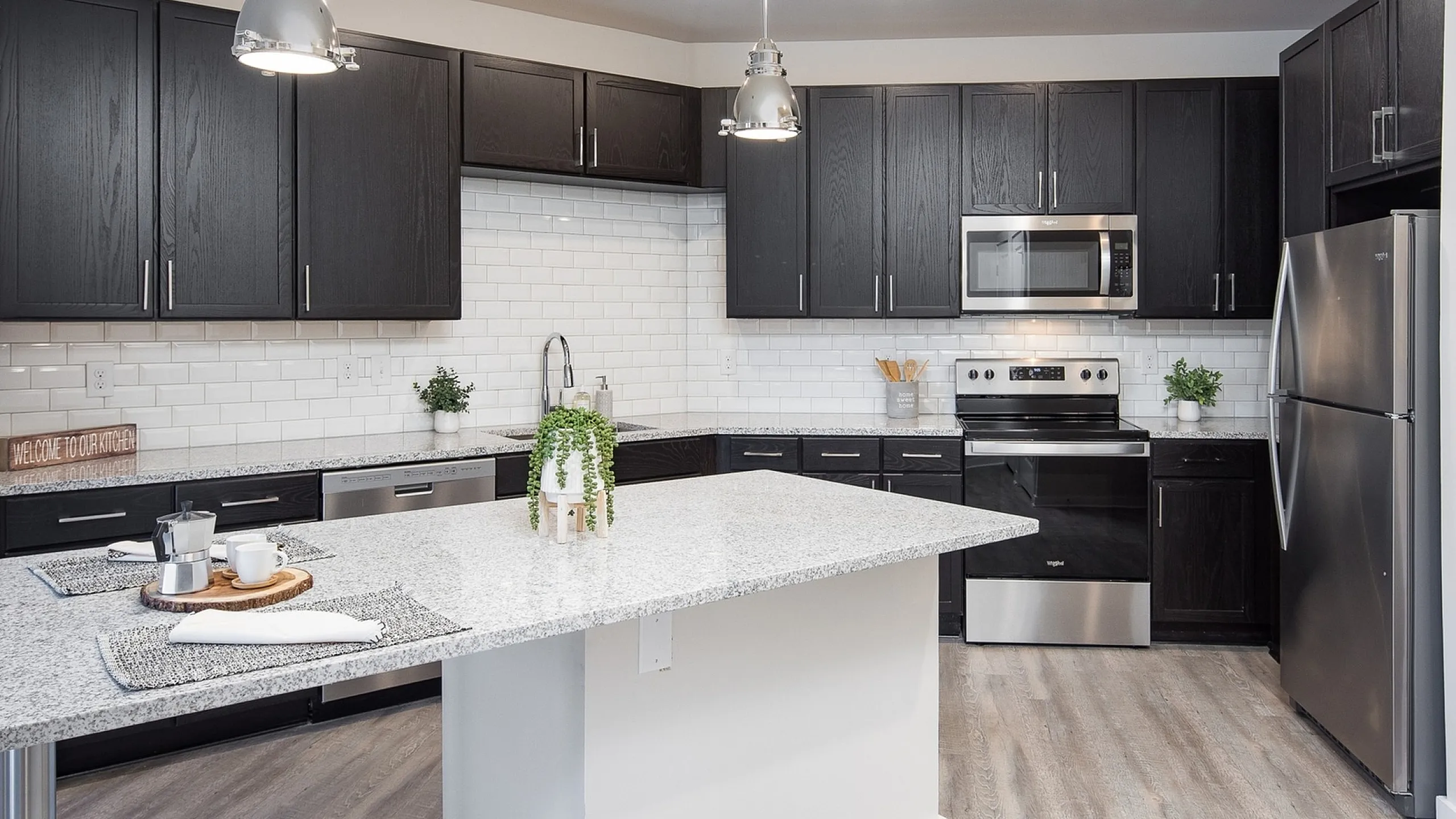 Sleek modern kitchen with dark cabinets, marble island, and stainless steel appliances.