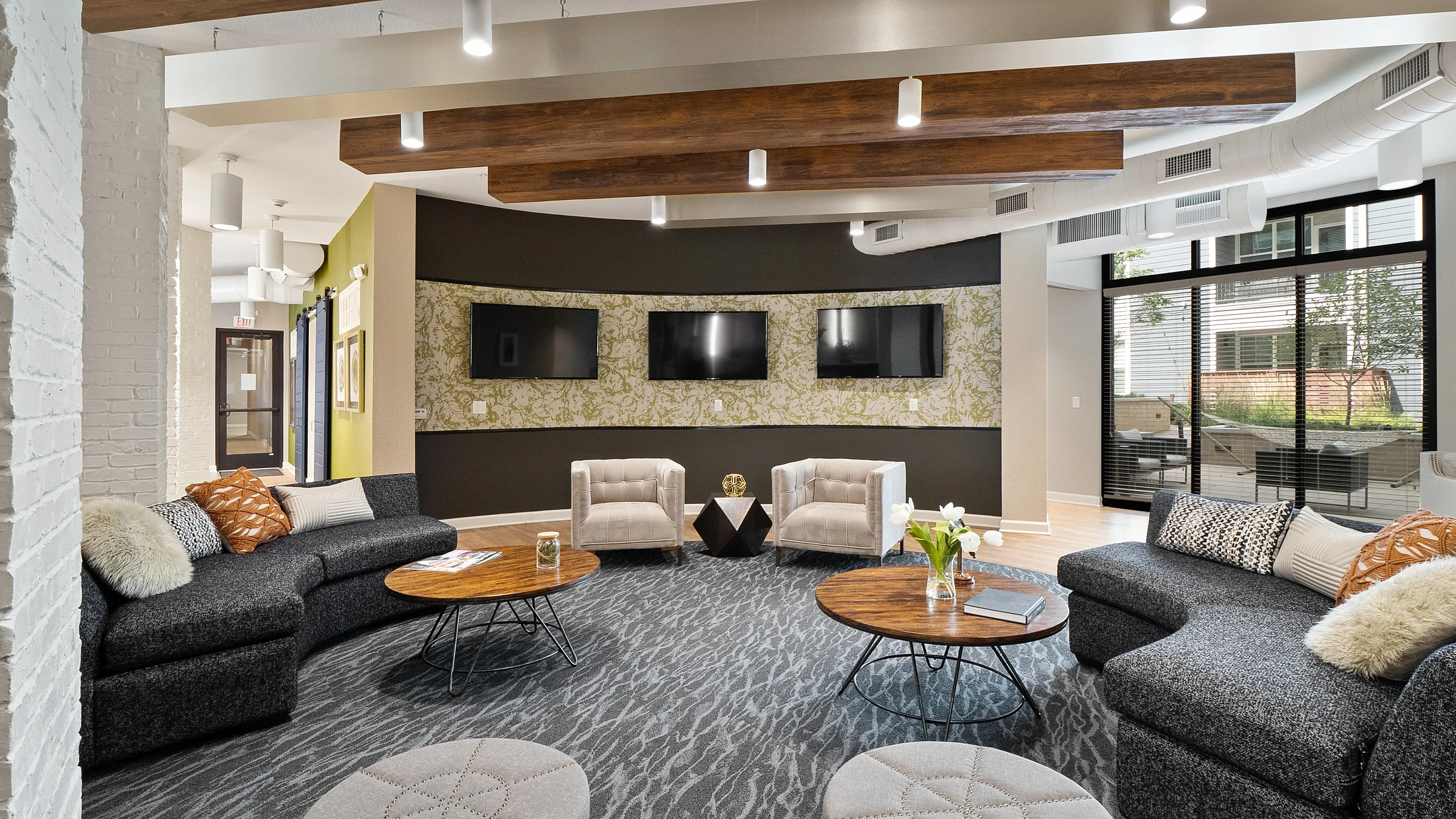 Elegant lounge area with stylish seating, wooden beam ceiling, and multiple flat-screen TVs.