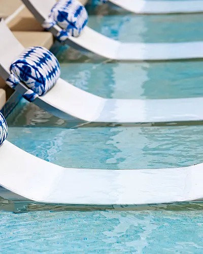 Chic poolside loungers with blue and white cushions, offering a serene and inviting ambiance.