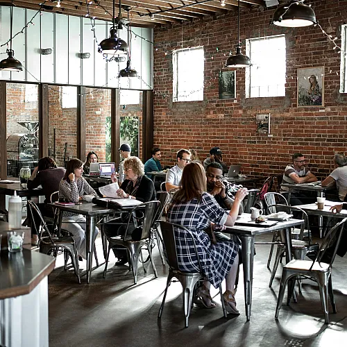 Inviting urban cafe with exposed brick walls, pendant lighting, and patrons enjoying their time.