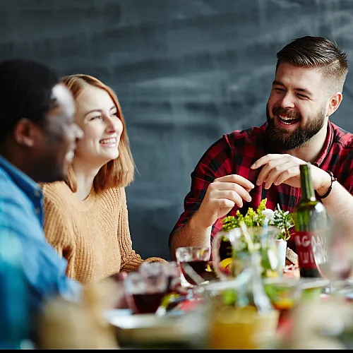Lively group of friends sharing a meal and laughter at a warmly decorated table.