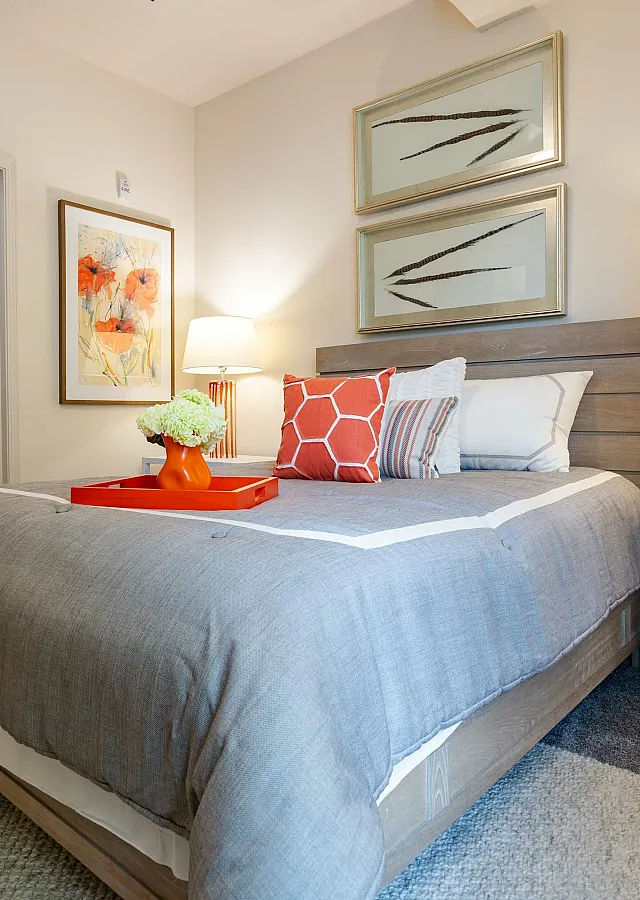 Inviting bedroom with modern decor, featuring a wooden bed, stylish nightstand, and artful wall decor.