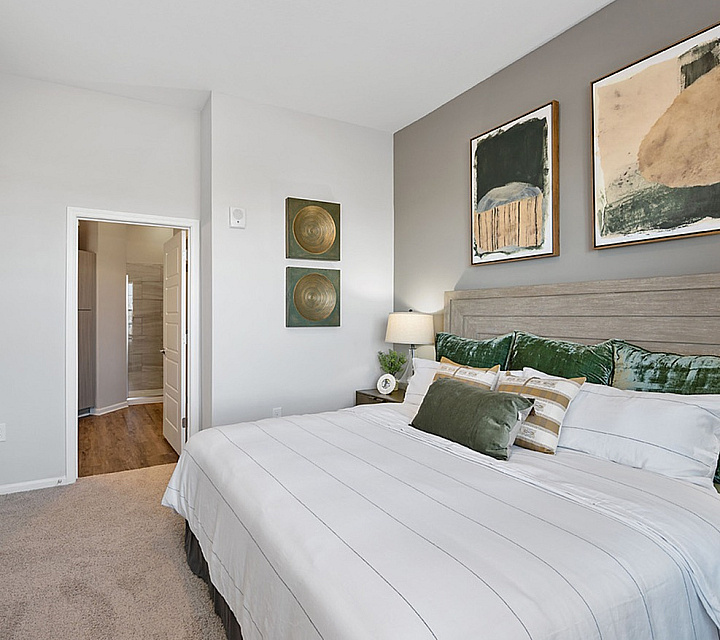 Elegant bedroom with plush bedding, chic wall art, and warm lighting, creating a cozy and inviting atmosphere.