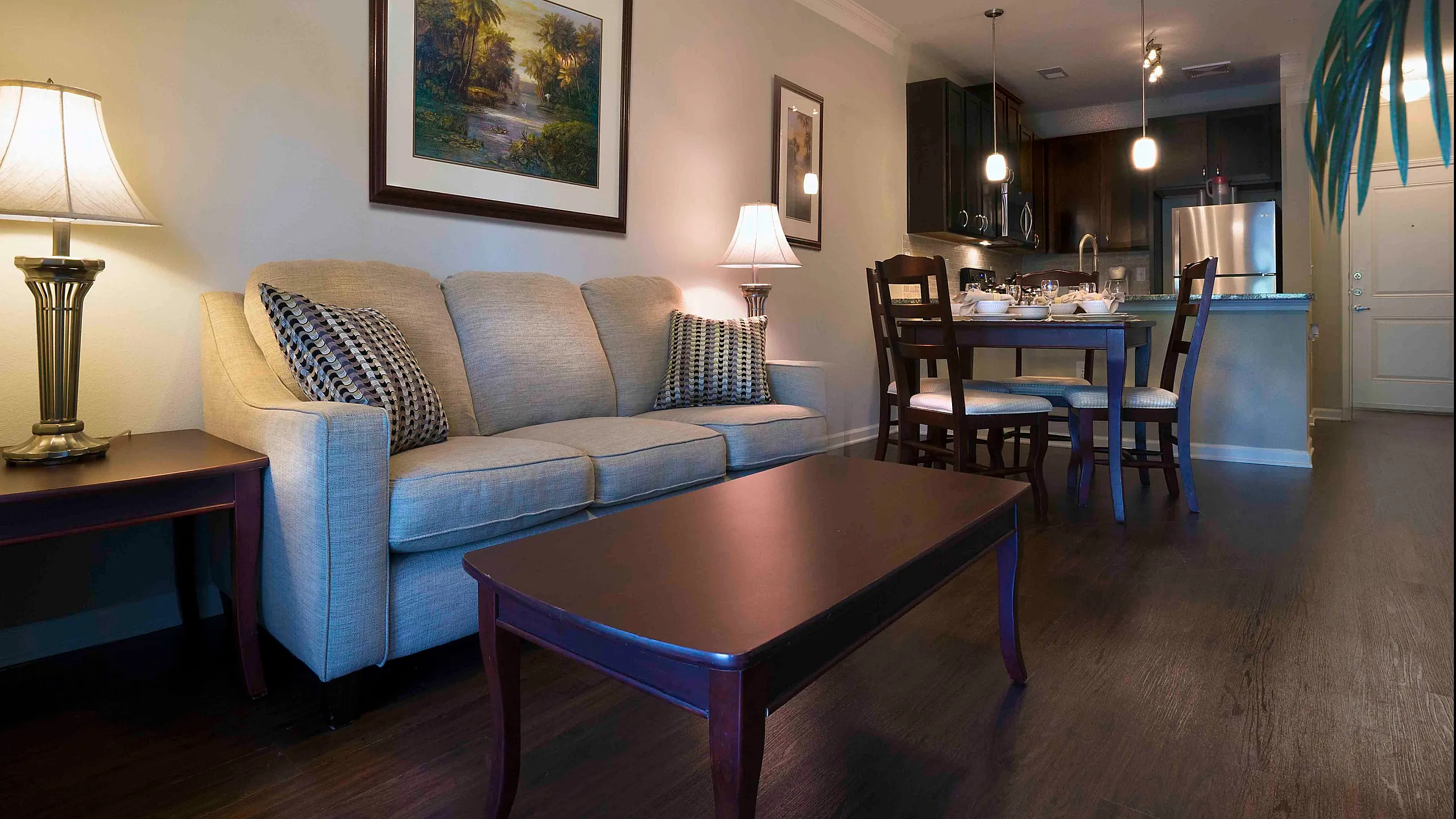 Cozy and inviting living space with a plush sofa, elegant lighting, and dining area next to a modern kitchen, ideal for relaxation and entertainment.