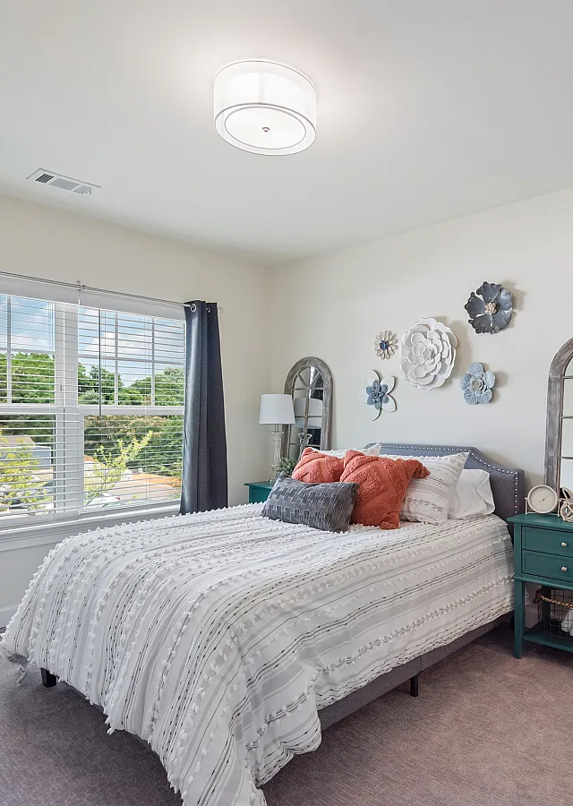 Inviting bedroom with a cozy bed, stylish decor, and large window offering natural light.