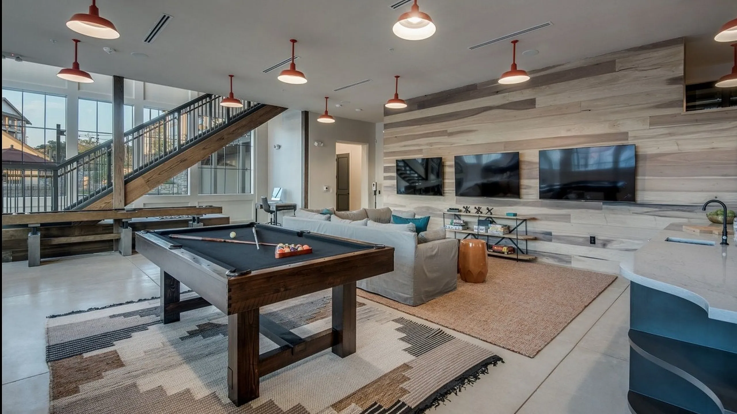 Luxurious entertainment room with modern pool table, cozy seating, and stylish decor under contemporary lighting.