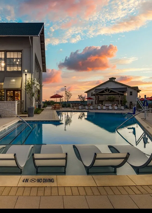 Elegant poolside view at sunset featuring luxurious lounge chairs and modern architecture, perfect for relaxation and leisure.