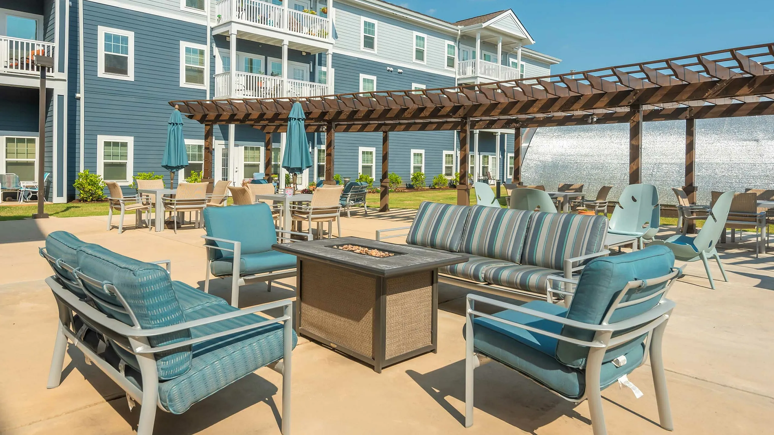 Charming apartment complex with a stylish outdoor seating area, featuring comfortable chairs and inviting pergola for relaxation.