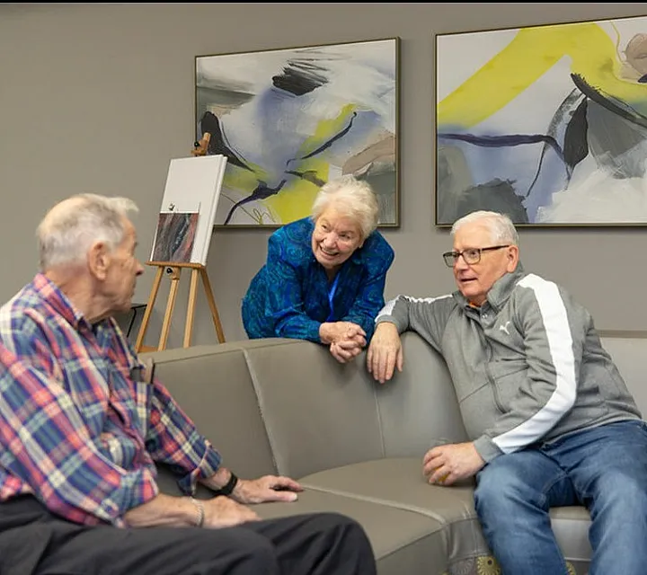 Warm and inviting common area with residents enjoying a lively conversation, surrounded by contemporary art and comfortable seating.