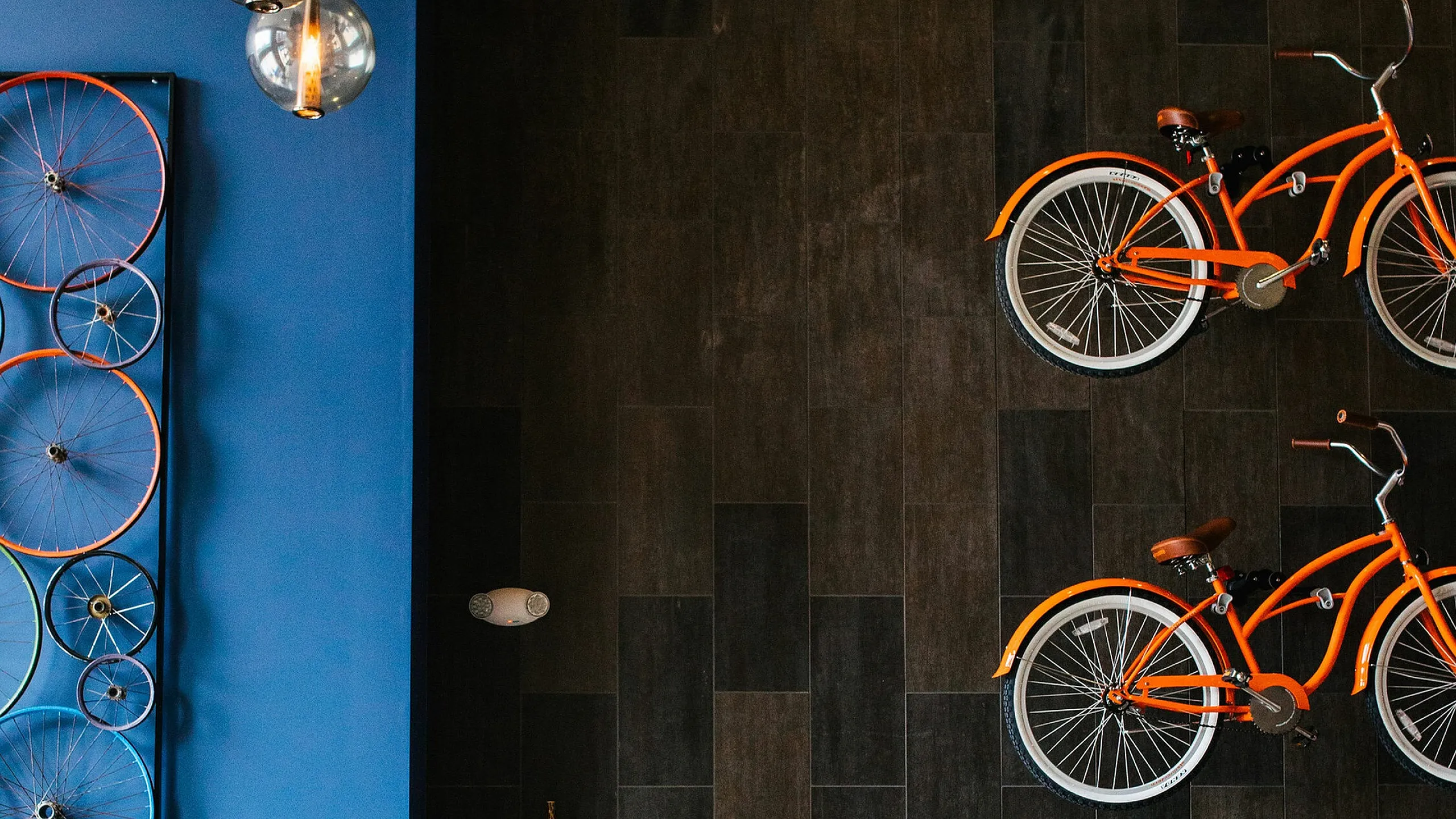 Chic and modern kitchen area with stylish hanging lights, vibrant bicycle-themed decor, and cozy bar stools in an urban apartment setting.
