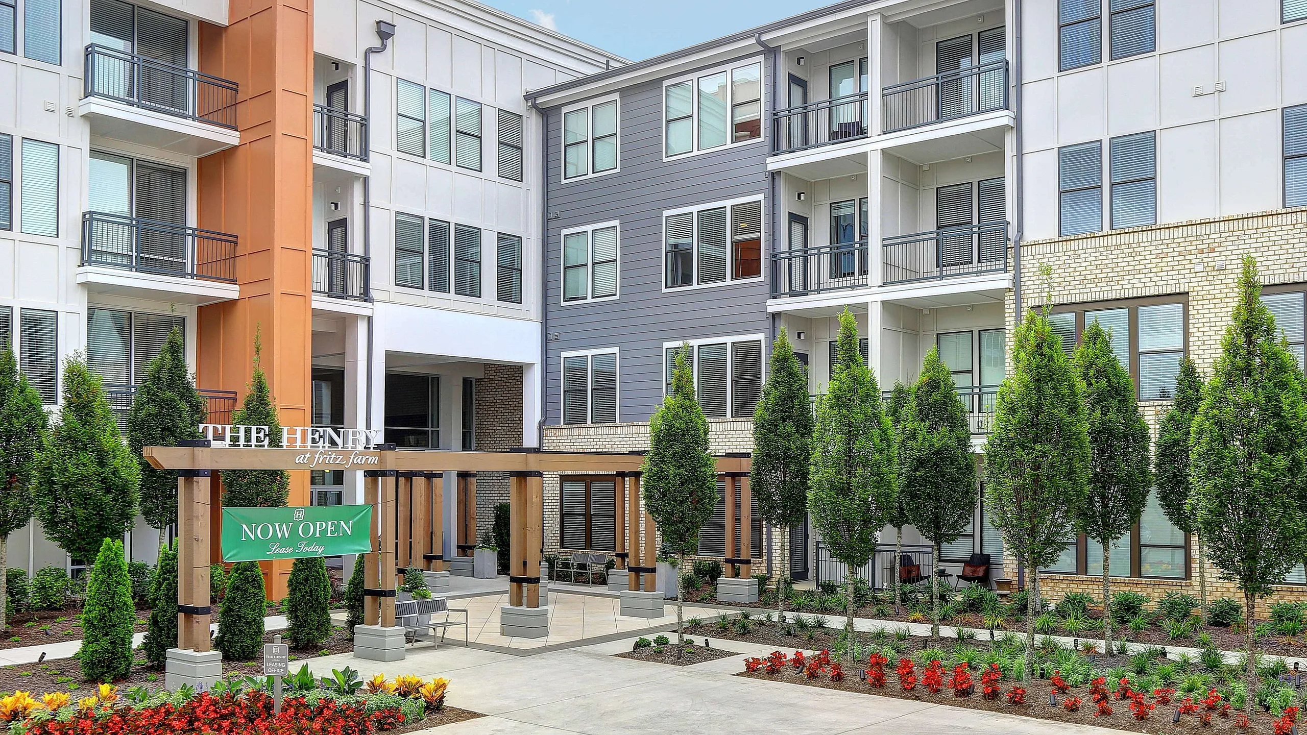 Modern apartment complex with elegant architecture, landscaped gardens, and welcoming outdoor seating area.