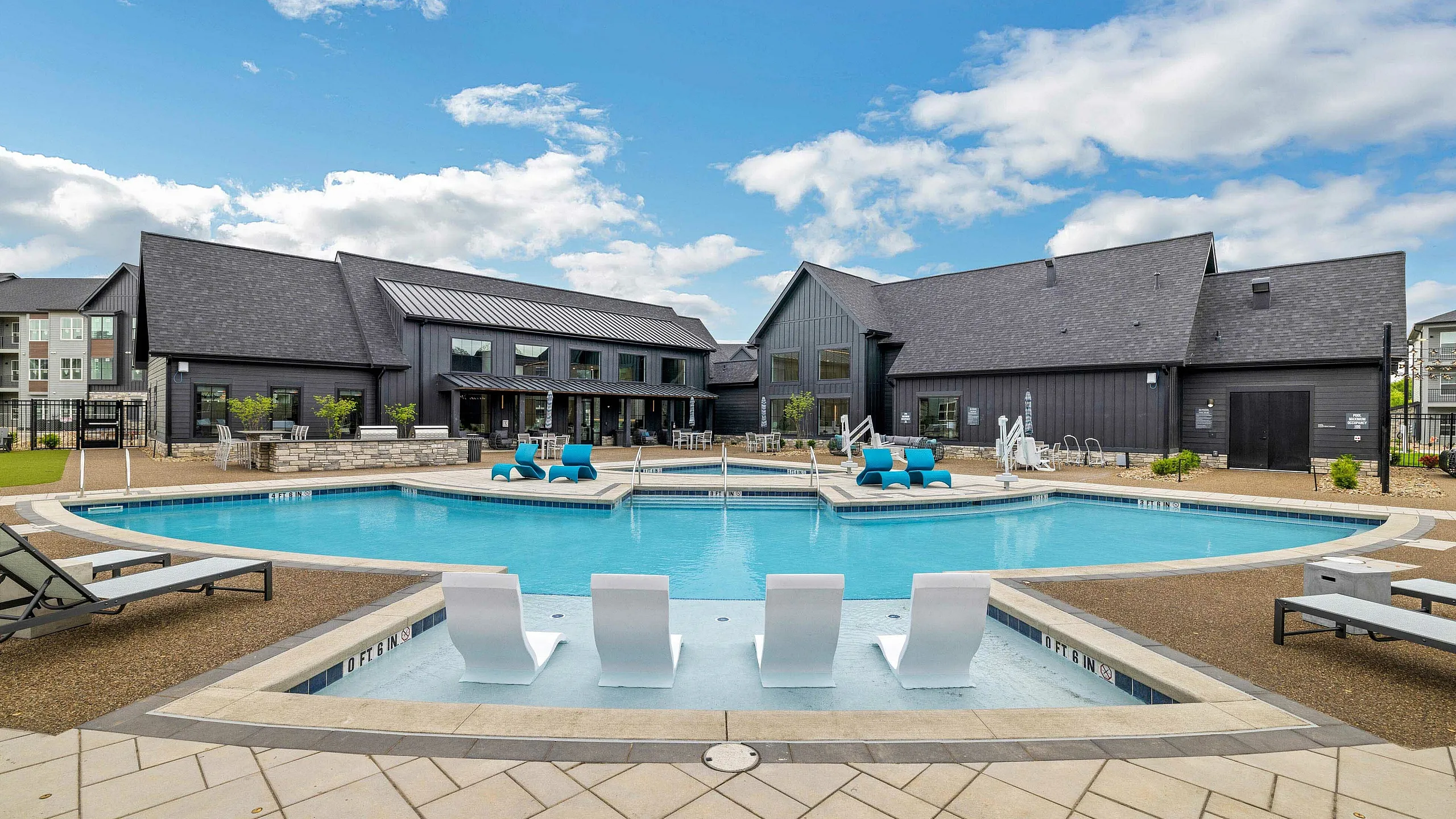 Luxurious outdoor pool area featuring comfortable lounge chairs and modern architecture under a bright blue sky.