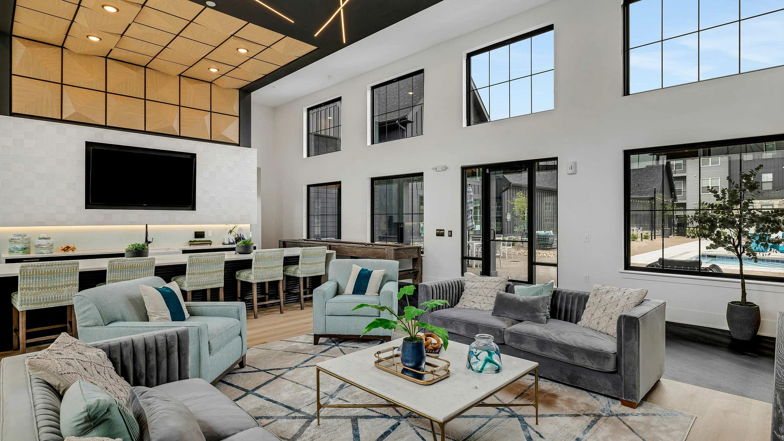 Modern and spacious living area with sleek decor, high ceilings, and large windows showcasing a vibrant view of the outdoors.