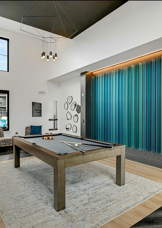 Chic recreational room with a sleek pool table, modern decor, and a vibrant blue accent wall, perfect for entertainment and relaxation.