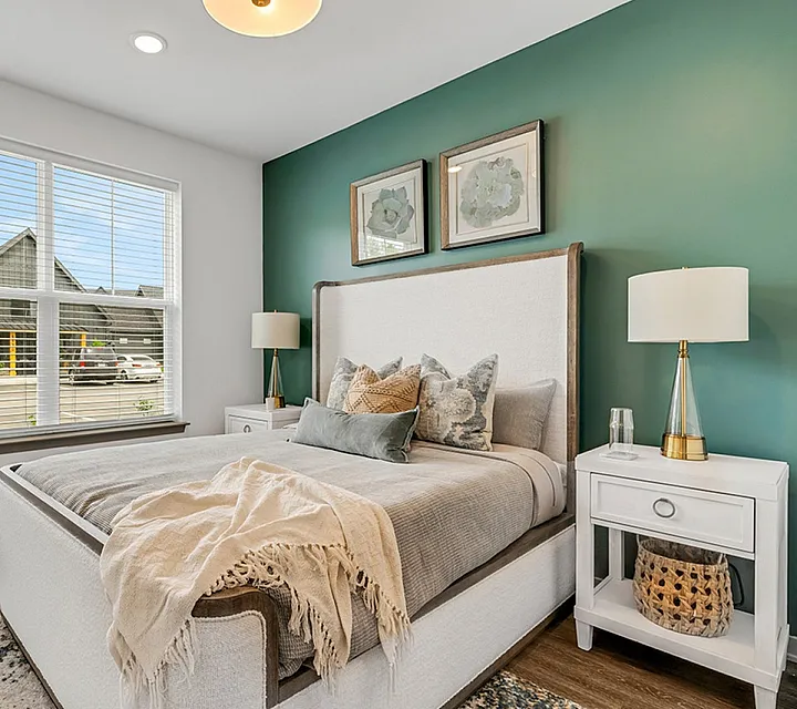 Inviting bedroom with modern decor, lush green accent wall, and large window brightening the space.