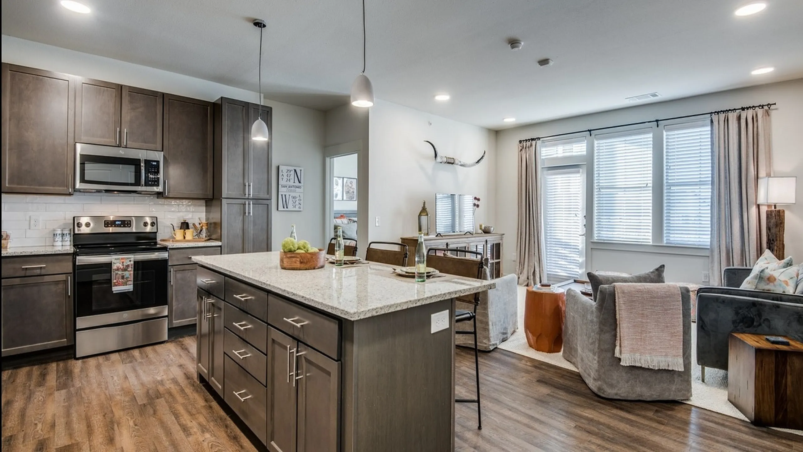 Modern open-concept kitchen and living room with granite countertops, sleek cabinetry, and abundant natural light.