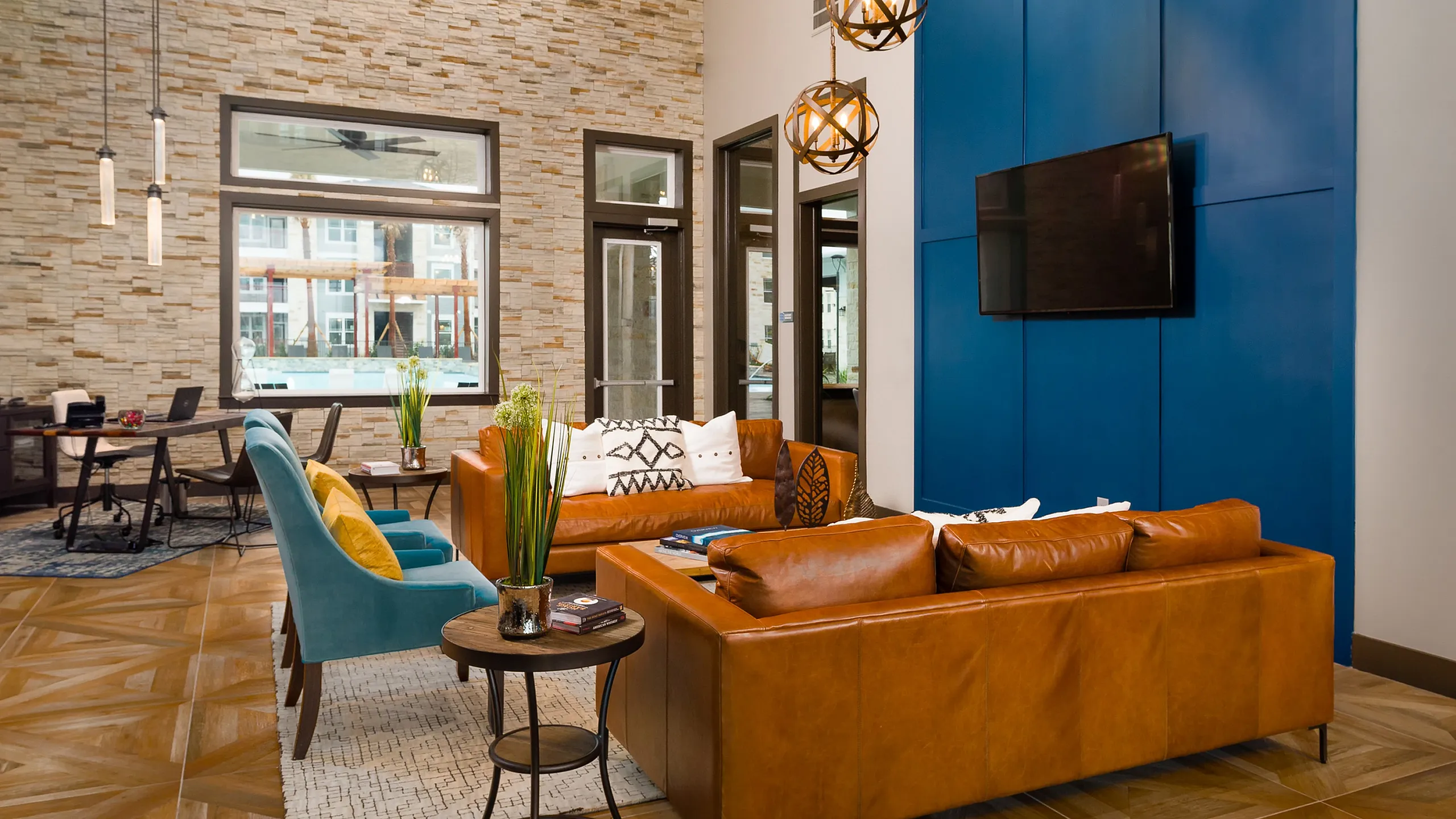 Stunning modern living room with vibrant blue accent wall, elegant pendant lights, and luxurious leather couches for a cozy and stylish ambiance.