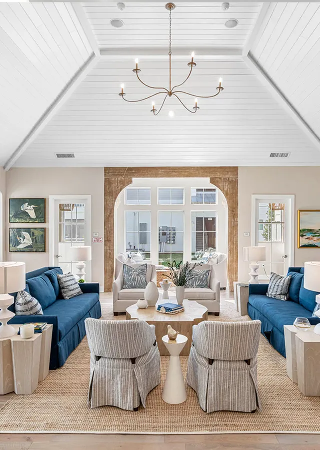 Elegant living room with vaulted ceiling, chic chandelier, cozy seating, and natural light creating a warm, inviting ambiance.