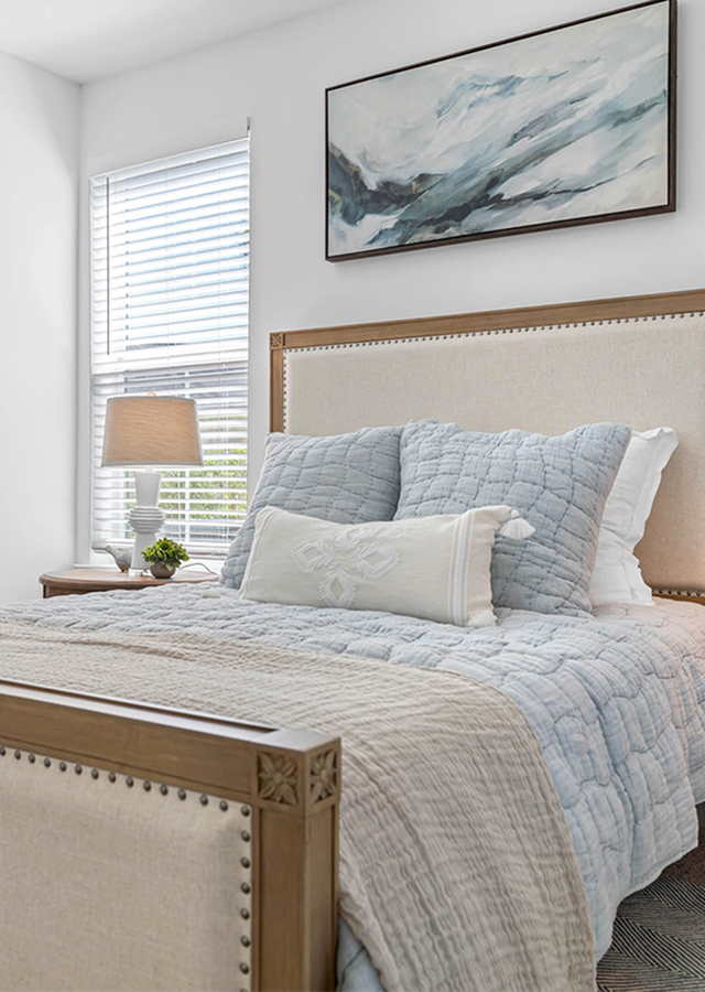 Serene bedroom with elegant decor, featuring a cozy bed with pastel linens and a large window inviting natural light.