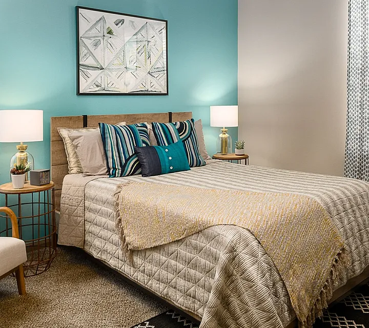 Inviting bedroom with a cozy bed, vibrant pillows, and stylish decor, bathed in warm ambient lighting.