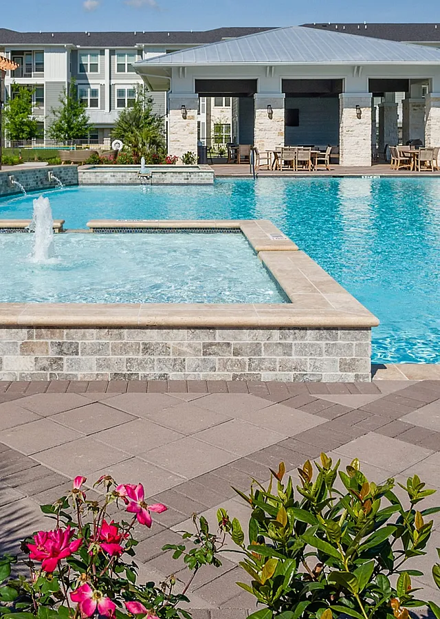 Luxurious outdoor pool area with sparkling water, elegant patio seating, and vibrant flowers, perfect for relaxation and entertainment.